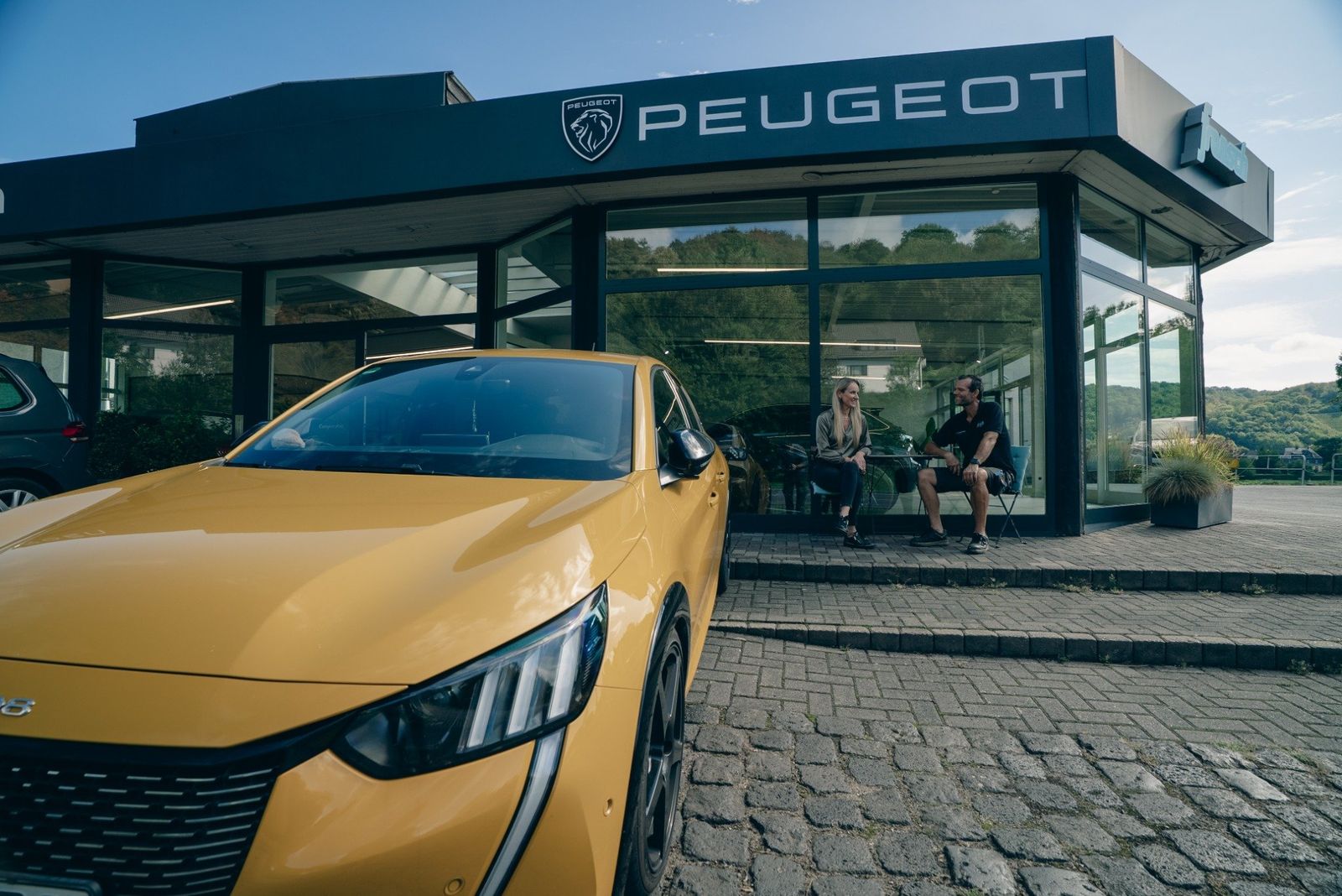 Das Autohaus Frensch in Remagen-Oberwinter mit Peugeot-Schriftzug, im Hintergrund die Hügel am Rhein
