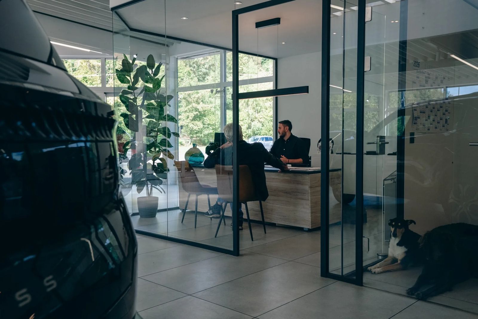 Eugen Kessler im Verkaufsgespräch mit einem Kunden im gläsernen Büro des Autohauses